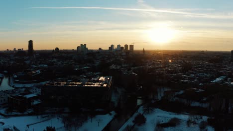 Vista-Aérea-De-Utrecht-Durante-La-Puesta-De-Sol-Y-Un-Lago-Congelado-Con-Gente-Patinando-Sobre-Hielo