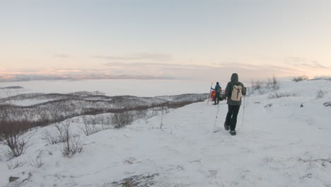 Wanderer-Mit-Schneeschuhen-Und-Stöcken,-Die-Bei-Sonnenaufgang-In-Der-Natur-In-Nordschweden-Auf-Einem-Berg-Wandern