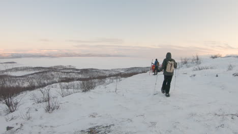 Hiker-with-snowshoes-and-poles-walking-on-a-mountain-during-sunrise-in-the-nature-in-northern-Sweden