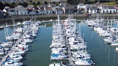 Sailboats-and-yachts-moored-along-Conwy-marina-luxury-waterfront-aerial-view-high-orbit-right
