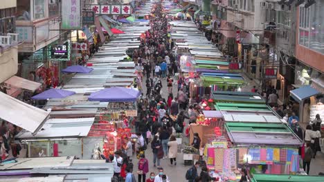 Large-crowds,-hundreds-of-shoppers,-walk-through-the-Fa-Yuen-street-market-stalls-as-they-look-for-bargain-priced-vegetables,-fruits,-gifts,-and-fashion-goods-in-Hong-Kong