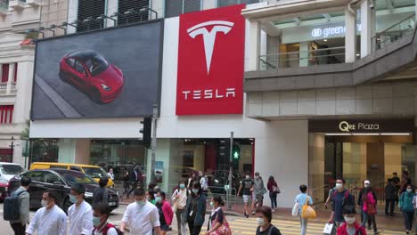 Die-Menschen-Gehen-Durch-Einen-Zebrastreifen-Vor-Dem-Offiziellen-Autorisierten-Autohändler-Der-American-Electric-Company-Car-Tesla-Motors,-Der-In-Hongkong-Zu-Sehen-Ist