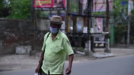 Asian-Indian-man-wearing-mask-and-hat-walks-on-road-during-lockdown-for-covid-19,-corona-quarantine,-slow-motion