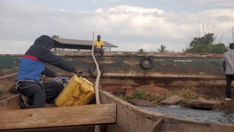 Young-African-man-driving-a-traditional-wooden-boat-with-a-petrol-engine-on-Lake-Victoria