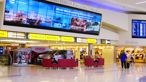 John-Glenn-International-Airport,-Terminal,-passengers-check-in-with-a-flight-update-screen