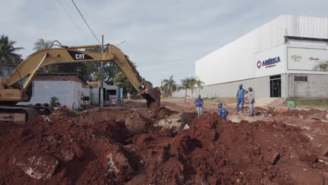 Wide-panning-shot-of-an-excavator-and-crew-digging-on-a-construction-site