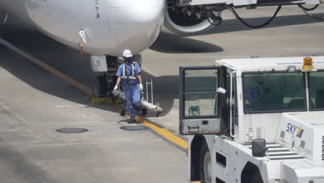 Bodenarbeiter-Auf-Dem-Rollfeld-Des-Flughafens,-Die-Sich-Darauf-Vorbereiten,-Ein-Passagierflugzeug-Der-Boeing-737-In-Tokio,-Japan,-Abzuschleppen