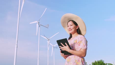 Asiatische-Junge-Frau-Mit-Digitalem-Tablet-Im-Feld-Im-Hintergrund-Windkraftanlagen