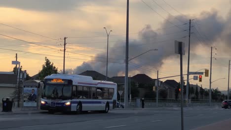 Bust-stopping-at-local-station-with-smoke-in-the-background