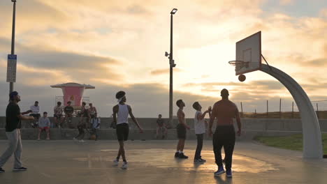 Gruppen-Von-Männern-Spielen-Basketball-Und-Sitzen-Auf-Einer-Bank-Am-Basketballplatz-Während-Des-Sonnenuntergangs-In-Imperial-Beach,-Kalifornien-City