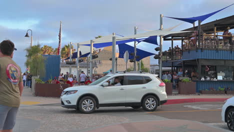 Multitud-De-Personas-Cenando-En-Mike-Hess-Brewing-En-Imperial-Beach,-California-Con-Auto-Blanco-Conduciendo-En-La-Carretera