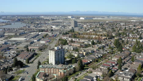 Aerial-flying-over-South-Vancouver-toward-the-YVR-airport-as-a-plane-flies-in-to-land