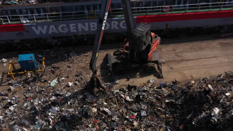 Eine-Mechanische-Greifmaschine-Nimmt-Altmetall-Auf-Und-Lässt-Es-Zum-Transport-Und-Recycling-In-Einen-Schiffscontainer-Fallen