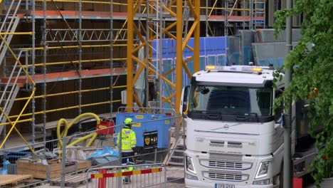 Construction-Site-Worker-and-Truck-Offloading-Material-for-Building-in-Gothenburg,-Sweden