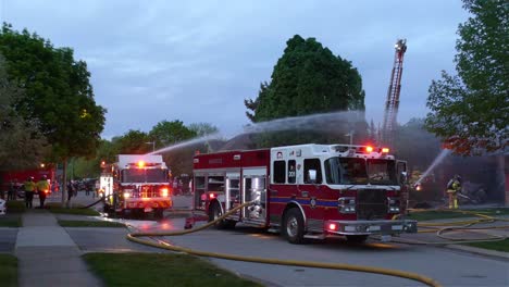 Bomberos-Y-Bomberos-Rociando-Agua-Sobre-El-Fuego-De-Una-Casa-De-Un-Camión-De-Bomberos