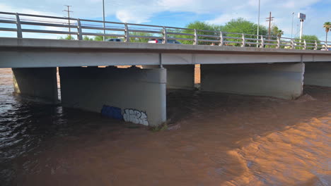 Vehículos-Que-Pasan-Por-El-Puente-Sobre-El-Río-Embravecido-En-Tucson,-Arizona-Durante-El-Día