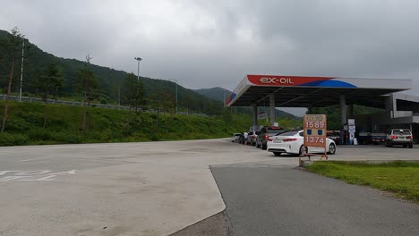 White-Car-Entering-Gasoline-Station-For-Refueling-In-South-Korea-On-A-Cloudy-Day