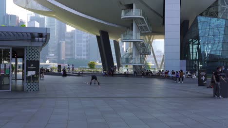 Joven-Chino-Patines-Recogiendo-Conos-De-Estilo-Libre-Del-Piso,-Marina-Bay,-Singapur