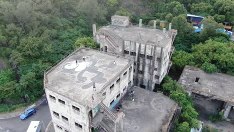 Hong-Kong-locals-on-an-abandoned-industrial-rooftop-decorated-with-a-large-graffiti-of-Felix-the-Cat,-Aerial-view