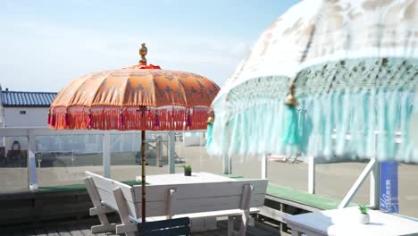Traditional-style-tassel-parasols-at-beachside-cafe,-reveal-shot
