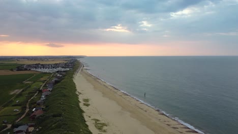 Aerial:-Eccles-sea-beach-with-fishing-village-at-Norfolk,-England---tilt-up-shot