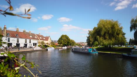 A-boat-on-the-river-Ely-Norfolk,-The-riverside-of-the-Great-Ouse-river-and-traditional-houses,-Ely,-Cambridgeshire,-Norfolk,-UK