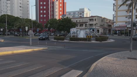 Kreisverkehr-Am-Strand-Von-Quarteira-Mit-Autos,-Die-Einen-Wasserbrunnen-Umkreisen