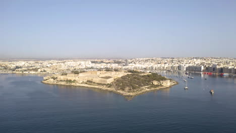 Island-with-a-stone-fortress-in-bay-of-Valletta-city,Malta,aerial-zoom