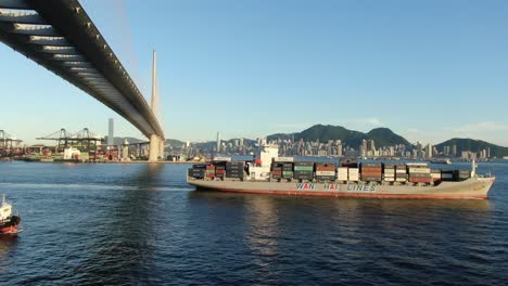 Large-Container-Ship-leaving-Hong-Kong-bay-under-Stonecutters-bridge,-Aerial-view