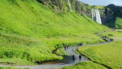 Tourists-walking-on-a-path-between-Seljalandsfoss-and-Gljufrabui-waterfalls-on-a-Sunny-day-in-Iceland