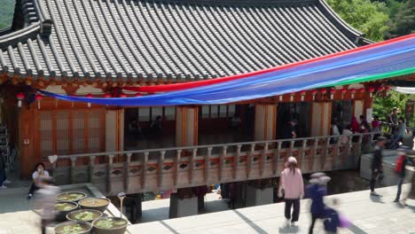 Tela-Colorida-Fuera-Del-Templo-Cheonggyesa-En-Uiwang,-Cheonggyesan,-Corea-Del-Sur-Con-Visitantes-Enmascarados-Durante-El-Cumpleaños-De-Buda-En-Una-Pandemia