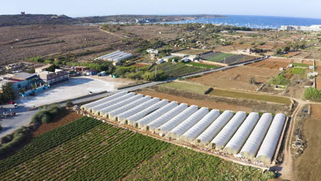 Campo-De-Tierras-De-Cultivo-Costeras-Con-Silos,-Mar-De-Malta,-Zoom-Aéreo