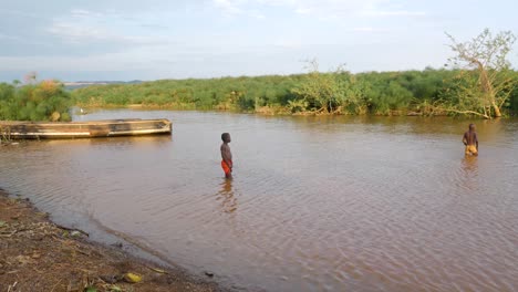 Zwei-Junge-Afrikanische-Jungen-Schwimmen-Im-Sumpf-Im-Viktoriasee-Mit-Einem-Traditionellen-Hölzernen-Fischerboot