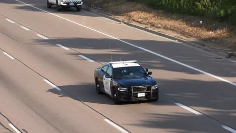 Police-officer-vehicle-leaving-crash-scene-in-highway,-follow-up-view