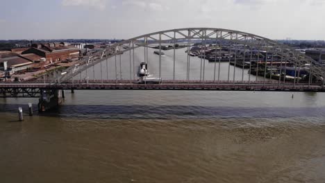 Arched-Bridge-Over-Noord-River-Canal-With-Ships-Traveling-In-Alblasserdam-In-The-Netherlands