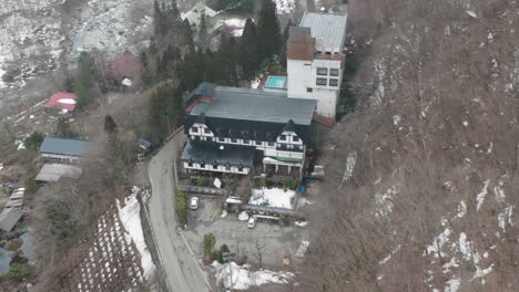 Vista-Aérea-Del-Hotel-De-3-Estrellas-De-Aguas-Termales-Con-Nieve-En-Una-Montaña