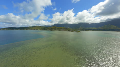 Flying-Over-Sparkling-Kaneohe-Bay-Towards-Lush-Mountains-of-Oahu,-FPV-Drone-Over-Ocean-and-Land