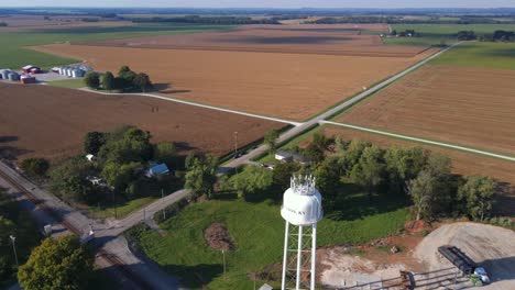 Imágenes-Aéreas-De-Drones-De-Rotación-Rápida-De-4k-De-Una-Granja-Donde-Se-Puede-Ver-Una-Torre-De-Agua-Y-Muchos-Silos-En-Un-Entorno-Rural