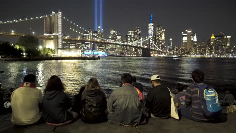 Grupo-De-Personas-Se-Sientan-Y-Ven-Las-Luces-Conmemorativas-Del-11-De-Septiembre-En-La-Ciudad-De-Nueva-York