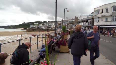 People-enjoying-a-summer-day-besides-the-harbour-in-St-Ives,-Cornwall,-UK