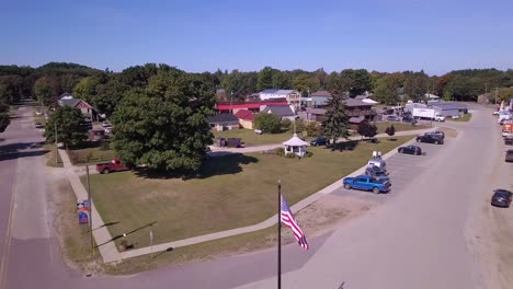 Bandera-Estadounidense,-Calles-Y-Casas-En-Grand-Marais,-Michigan,-Antena-Delantera