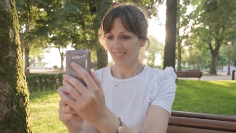 Una-Mujer-Filmando-Un-Video-Selfie-Usando-Su-Teléfono-Mientras-Sonríe,-Toma-De-Mano