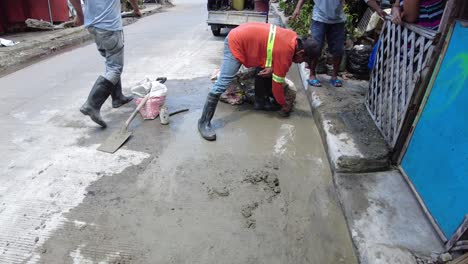 Foremen-wearing-safety-reflective-vests-used-their-shovel,-mixed-cement,-and-demolition-hammer-to-perform-excavation-beside-the-road-gutter-to-install-new-water-piping-from-the-main-water-line