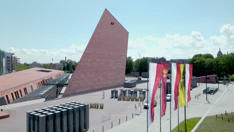 Aerial-orbiting-over-polish-national-flags-on-the-territory-of-Gdansk-Museum-of-Second-World-War,-flags-of-Poland-and-city-waving-on-flagpoles