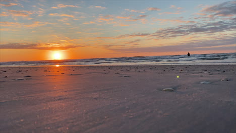 Malerischer-Strand-Bei-Sonnenuntergang-Mit-Einer-Person,-Die-Im-Ozean-Steht