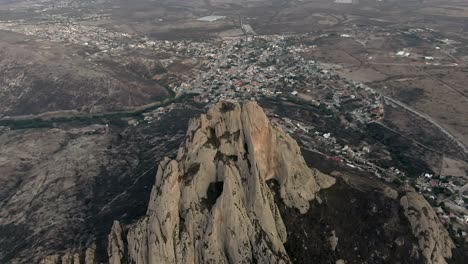 Aerial-View-Of-Peña-de-Bernal,-Mountain-Peak-With-Bernal-Village-In-Background-In-Queretaro,-Mexico