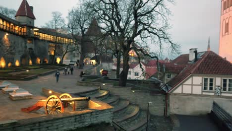 Estonia,-Tallinn,-Tallitor's-Tower-and-part-of-the-Old-City-with-tourists-at-night