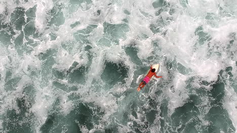 Top-View-Of-Male-Surfer-Lying-And-Swimming-On-A-Surfboard-Afloat-On-Wavy-Ocean-Surface-In-La-Ticla,-Mexico