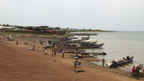 Poor-African-fishermen-preparing-wooden-canoes-to-go-out-fishing,-Lake-Volta