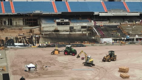 Santiago-Bernabeu-Stadium-Renovation---Tracked-Loader-And-Tractor-With-Workers-Working-On-Bleachers-Of-Stadium-In-Madrid,-Spain